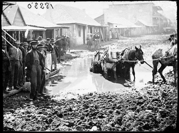 Horse and cart bogged in what was originally a gold digging outside Meares flooded Criterion Store, Clarke Street, Hill End